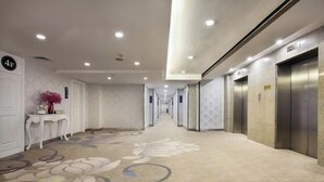 A hotel corridor with a carpeted floor, a reception desk, and an elevator. - Minhang Hotel (Guilin Railway Station & Elephant Trunk Hill Park Branch) (Guilin)