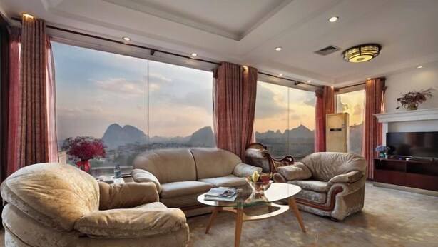 A spacious living room with a large window offering a mountain view, a fireplace, and a television. - Minhang Hotel (Guilin Railway Station & Elephant Trunk Hill Park Branch) (Guilin)