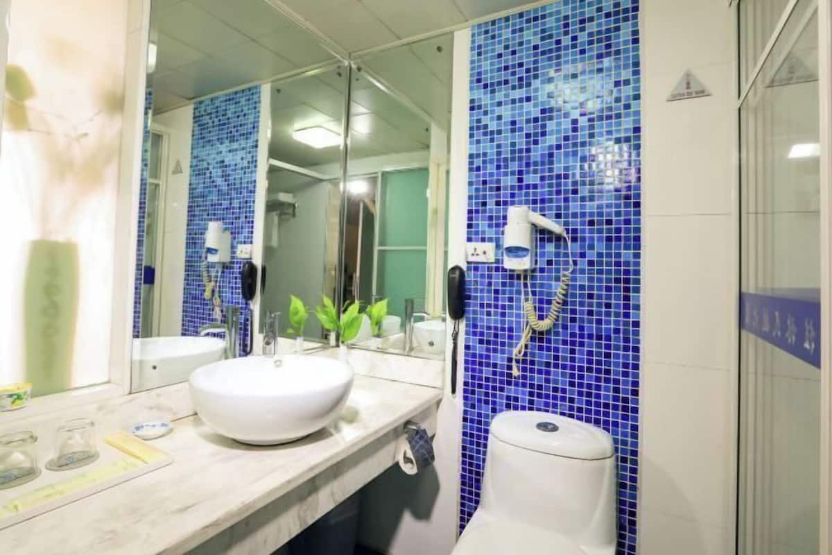 A bathroom with a white sink, mirror, and blue-tiled walls.