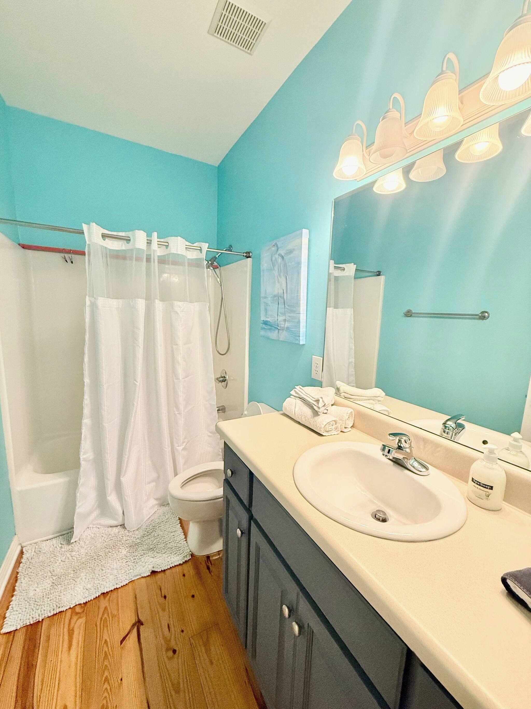 A bathroom with a shower, toilet, sink, and mirror.