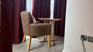 A room with a striped armchair, a small round table, and a power outlet on the wall. - Executive Single: Comfort for Solo Travellers in Blaby (Blaby)