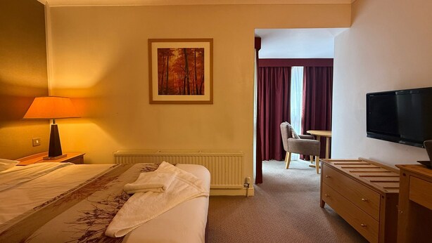 A hotel room with a bed, a desk, a television, and a painting on the wall. - Executive Single: Comfort for Solo Travellers in Blaby (Blaby)