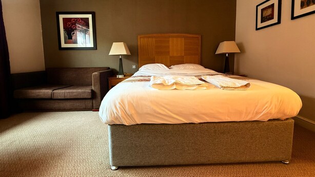 A hotel room with a bed, a sofa, two lamps, and a framed picture on the wall. - Relaxing Executive Double Room with Sofa in Blaby (Blaby)