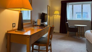 A hotel room with a wooden desk, a chair, a bed, a television, and a window with curtains. - Relaxing Executive Double Room with Sofa in Blaby (Blaby)