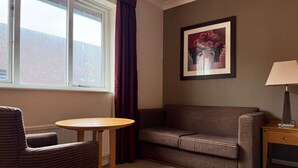 A room with a window, a framed picture, a sofa, a chair, a small table, and a lamp. - Relaxing Executive Double Room with Sofa in Blaby (Blaby)