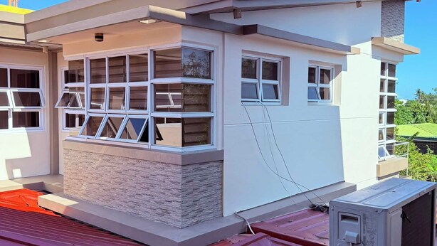A modern building with a flat roof, multiple windows, and a small balcony. - ValueNest Stay (Naga)