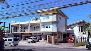 A multi-story building with commercial spaces on the ground floor, including a motor parts store and a water supply company. - ValueNest Stay (Naga)