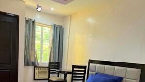 A bedroom with a bed, two chairs, a table, and a window with curtains. - ValueNest Stay (Naga)