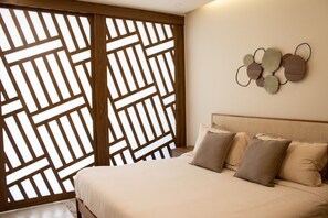 Ein Schlafzimmer mit Bett, Kissen, einem Kopfteil, einem Wandbild und einer Holzwand mit geometrischem Muster.