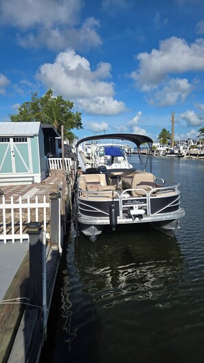 A boat docked at a marina with a covered seating area, a small building, and a clear sky. - Happier in the keys- waterfront tiny home in Key Largo (Key Largo)