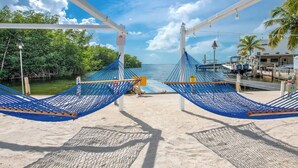 A beach view with hammocks, a dock, and a boat. - Happier in the keys- waterfront tiny home in Key Largo (Key Largo)