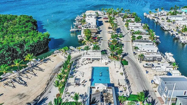 An aerial view of a coastal resort with a swimming pool, beach area, and marina. - Happier in the keys- waterfront tiny home in Key Largo (Key Largo)