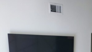 A television mounted on a wall with a wooden entertainment center below. - A bit of Tampa sunshine  (Tampa)
