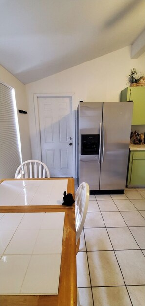 A kitchen with a stainless steel refrigerator, a white door, and a tiled floor. - A bit of Tampa sunshine  (Tampa)