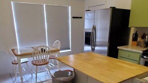 A kitchen with a wooden countertop, white cabinets, a ceiling fan, and a window with blinds. - A bit of Tampa sunshine  (Tampa)