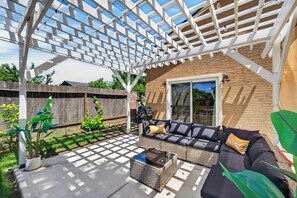 A covered patio with a white pergola, outdoor furniture, and a brick wall. - Elegant Mediterranean 3BR Haven Citrus Heights (Citrus Heights)