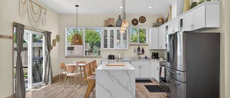 A modern kitchen with a central island, white cabinetry, and stainless steel appliances.