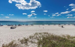 Una playa con arena, algunas personas y un cielo despejado.