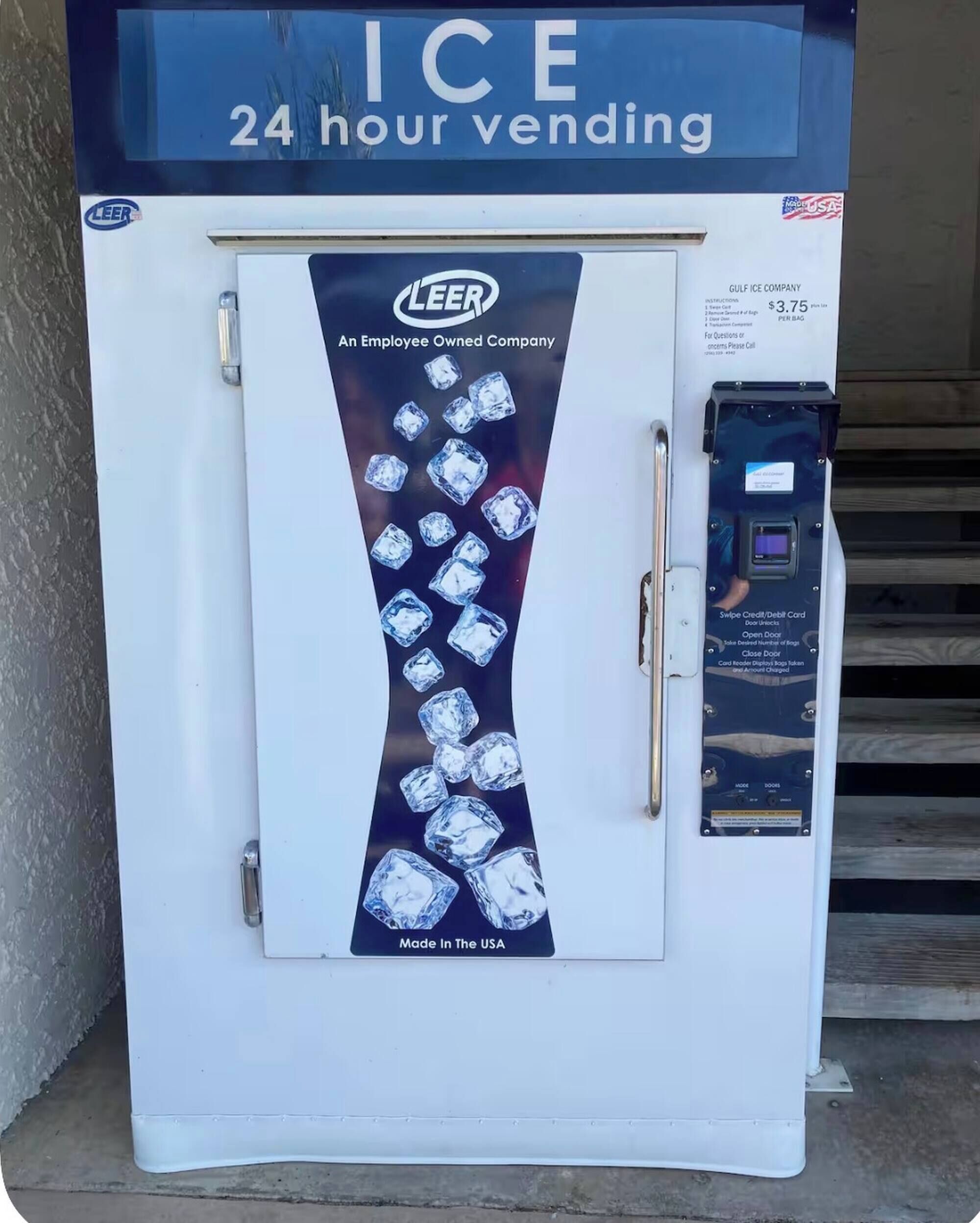 Ein Verkaufsautomat mit einem Schild, das '24-Stunden-Service' anzeigt, einem 'Gulf Ice Company'-Label und der Möglichkeit, mit Kredit- oder Debitkarte zu bezahlen.