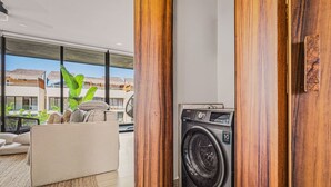 Un salón moderno con un sofá, una lavadora y vistas a una zona residencial.