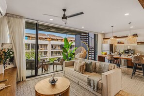 A modern living room with a sofa, a dining area, and a kitchen. - Quiet 2BR Penthouse w Private Pool | Gym | CoWork (Tulum)