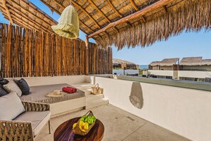 A rooftop terrace with a thatched roof, wicker furniture, and a fruit basket. - Quiet 2BR Penthouse w Private Pool | Gym | CoWork (Tulum)