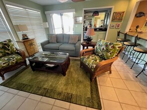A living room with a sofa, two armchairs, a coffee table, and a dining area with chairs. - Beachfront Sunset Haven w/ Big Balcony, Gulf View in Beautiful Perdido Key, FL (Pensacola)