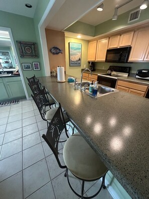 A kitchen with a granite countertop, stainless steel sink, and wooden cabinets. - Beachfront Sunset Haven w/ Big Balcony, Gulf View in Beautiful Perdido Key, FL (Pensacola)