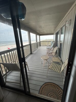 A covered deck with outdoor seating, a view of the beach, and a door leading to the interior. - Sunsets! Beachfront!  Gulf view! 2-bedroom condo in beautiful Perdido Key, FL (Pensacola)