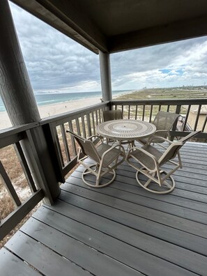 A covered outdoor area with a table and chairs, overlooking a beach. - Sunsets! Beachfront!  Gulf view! 2-bedroom condo in beautiful Perdido Key, FL (Pensacola)