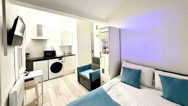 A modern hotel room with a bed, a small seating area, a kitchenette, and a washing machine. - London Camden studio sleeps 3 (London)