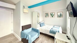 A bedroom with a bed, a desk, a chair, a wardrobe, and a television. - London Camden studio sleeps 3 (London)