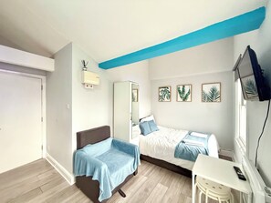 A bedroom with a bed, a desk, a chair, a wardrobe, and a television. - London Camden studio sleeps 3 (London)