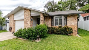 A single-story house with a brick facade, a garage, and a well-maintained lawn.