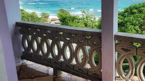 A balcony with a view of the ocean, a patterned floor, and a decorative railing.