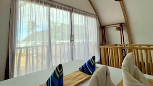 Quarto com teto arredondado, cama com almofadas, luminária pendente e janela com cortinas.