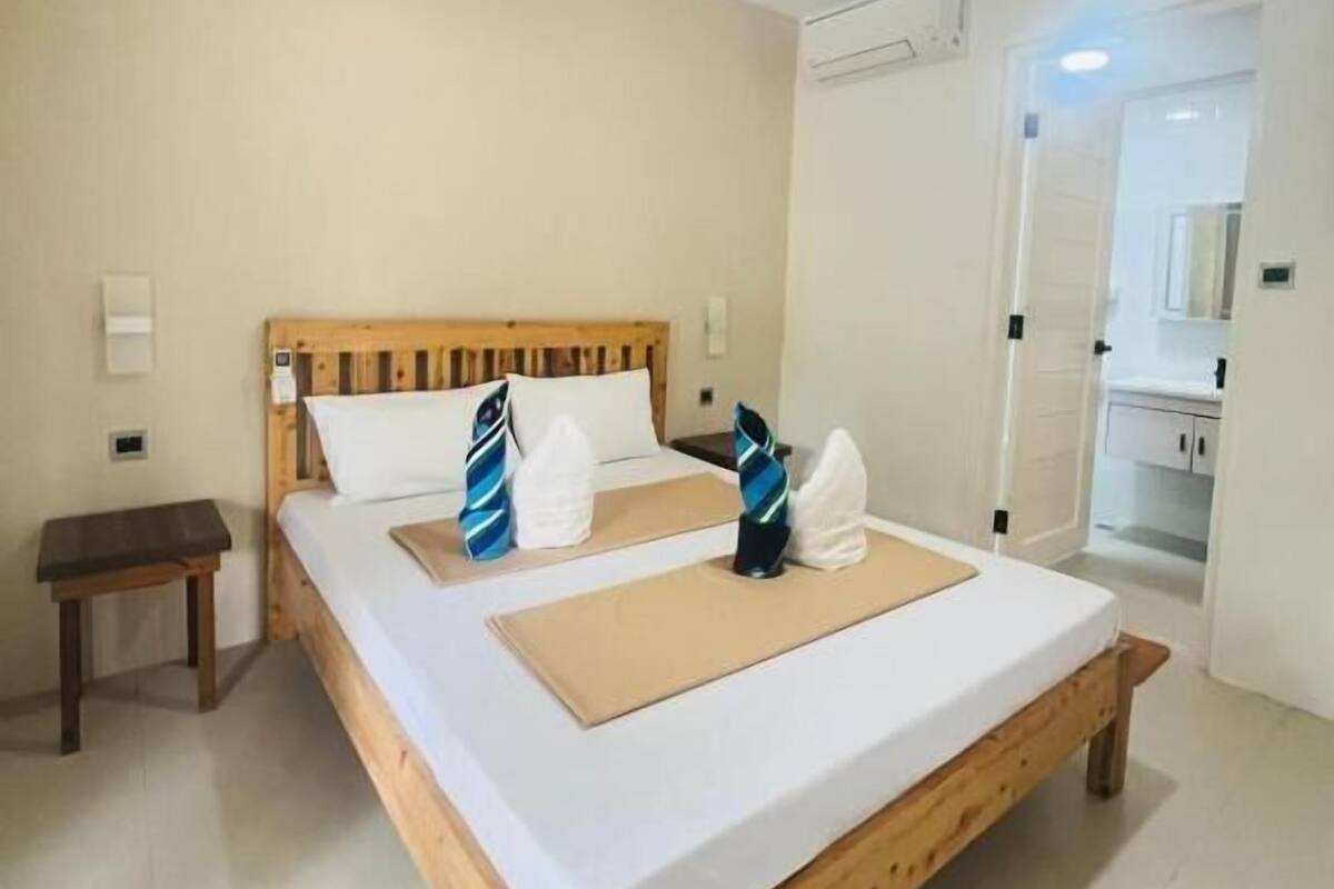 Ein Schlafzimmer mit einem Holzbett, weißen Leinen, einem Nachttisch und einem kleinen Beistelltisch.