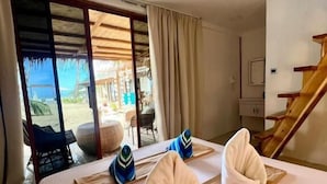 Quarto de hotel com cama, vista para o exterior, escada e área de refeições.