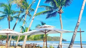 Pantai pribadi, pasir putih, kursi berjemur, dan payung pantai