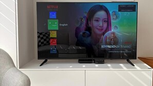 Ein Flachbildfernseher auf einer weißen Unterhaltungsecke mit Fernbedienung.