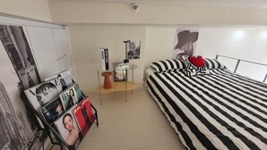 Ein Schlafzimmer mit einem Bett, einem kleinen Tisch, einem Stuhl und einem Bild an der Wand.