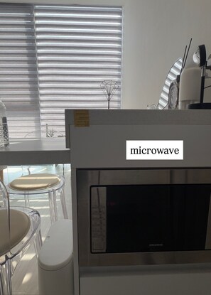 Une cuisine équipée d’un four à micro-ondes, d’une table en verre et d’une chaise.