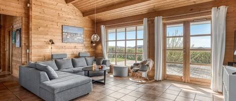 A log cabin interior with a gray sectional sofa, a round coffee table, and a rocking chair.
