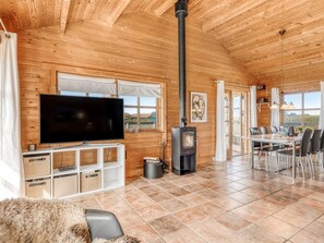Ein Holzblock-Interieur mit Fernseher, Kamin, Essbereich und großen Fenstern.
