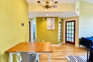 A dining area with a wooden table and chairs, a chandelier, and a painting on the wall.