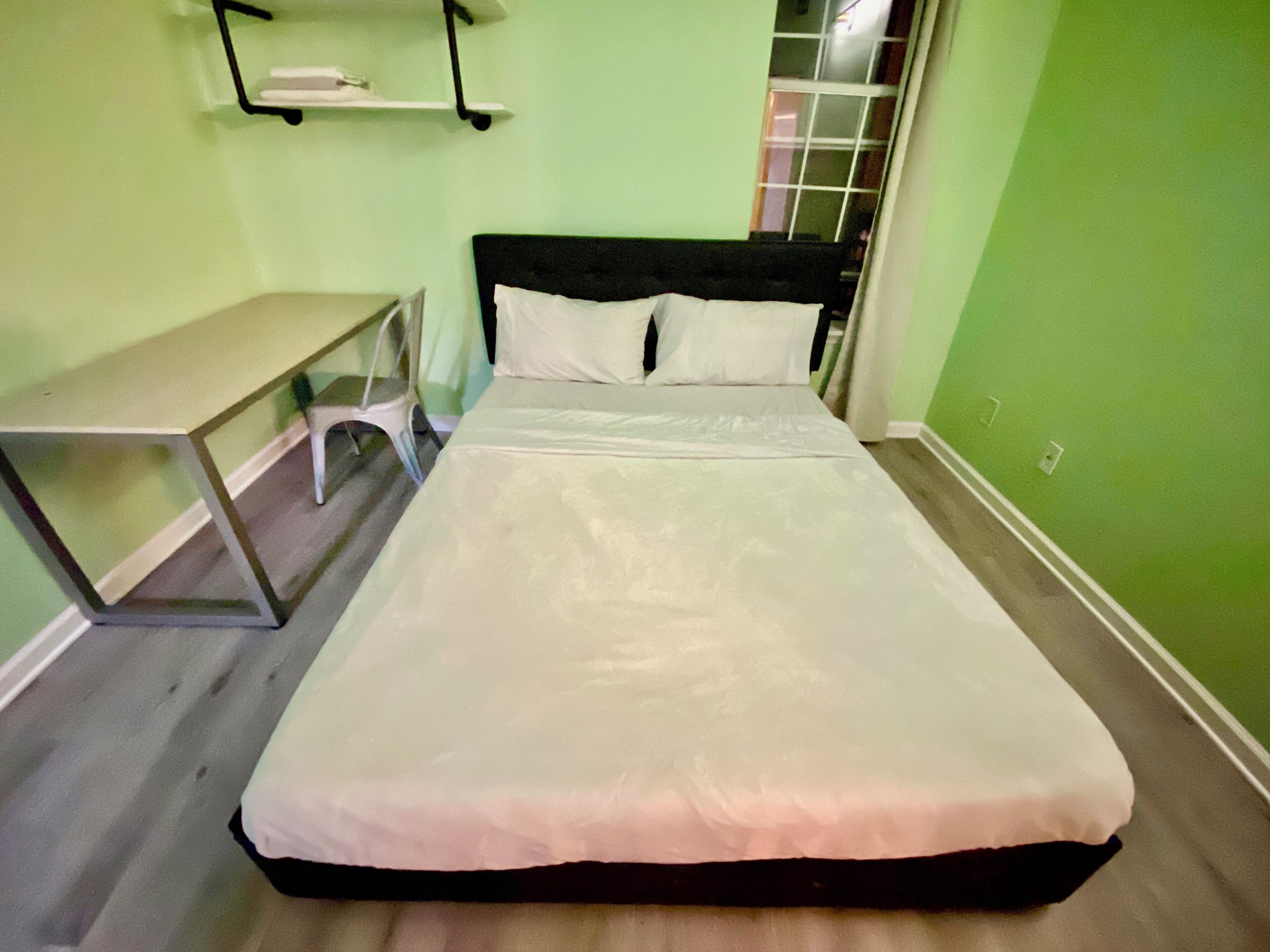 A room with a bed, a small table, and a chair.
