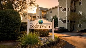 A sign for 'The Courtyard' with a modern building in the background. - Modern 2-Bedroom Apartment with Private Pool and Balcony in Wilmington (Wilmington)