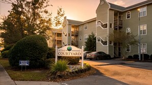 A multi-story residential building with a sign reading 'THE COURTYARD.' - Modern 2-Bedroom Apartment with Private Pool and Balcony in Wilmington (Wilmington)