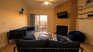 A living room with a sofa, a coffee table, a TV, and a balcony with a view. - Modern 2-Bedroom Apartment with Private Pool and Balcony in Wilmington (Wilmington)