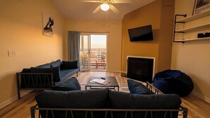 A living room with a sofa, a coffee table, a TV, and a balcony with a view. - Modern 2-Bedroom Apartment with Private Pool and Balcony in Wilmington (Wilmington)